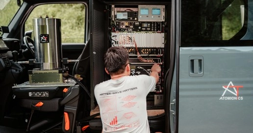 Person working inside a mobile sensing unit, adjusting electronic equipment mounted in a rack inside a vehicle.