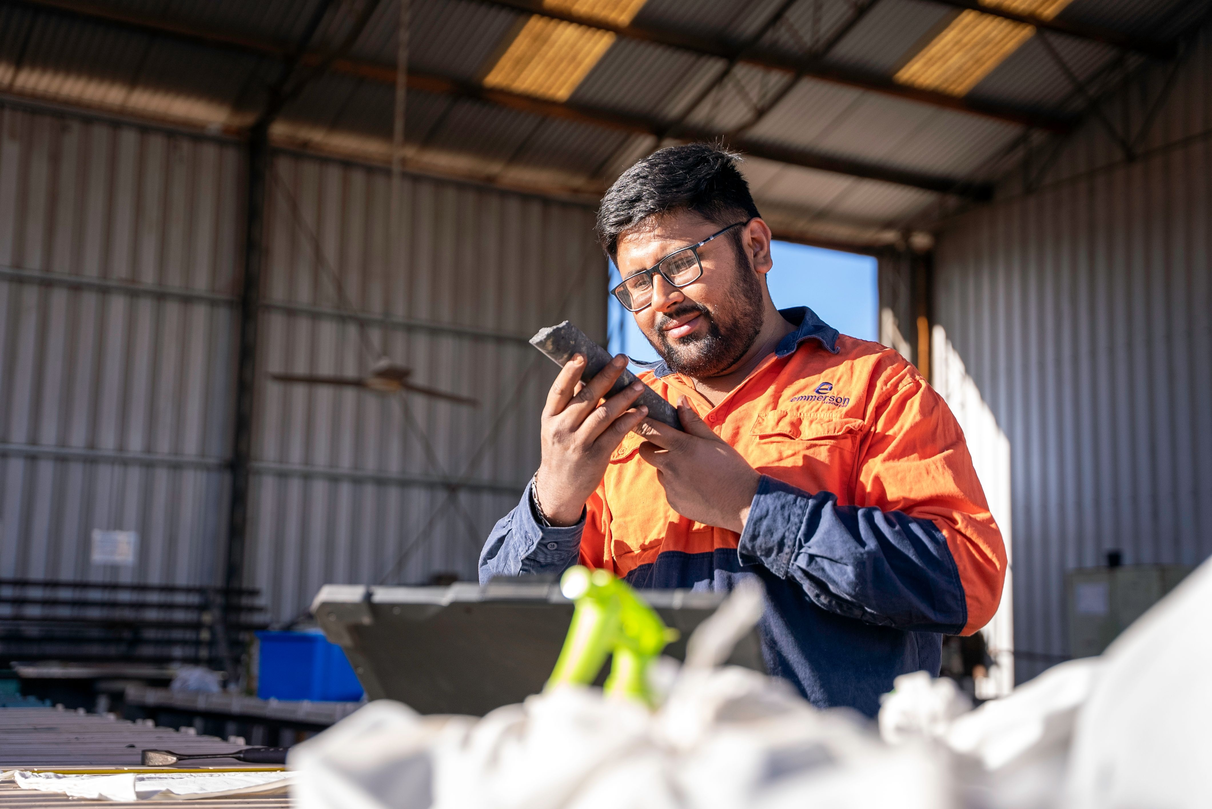 Worker inspecting a metal component inside an industrial workshop.