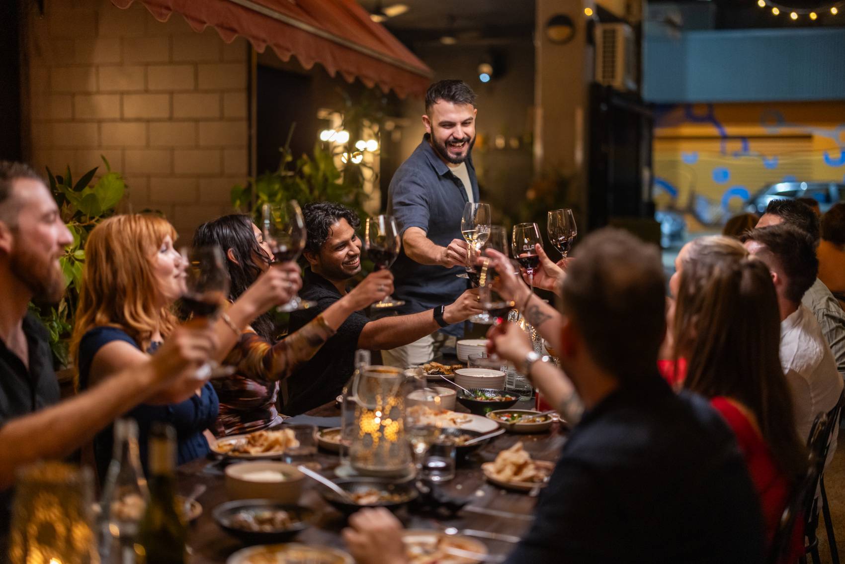 A group of friends enjoying a celebratory dinner and toasting with wine glasses.