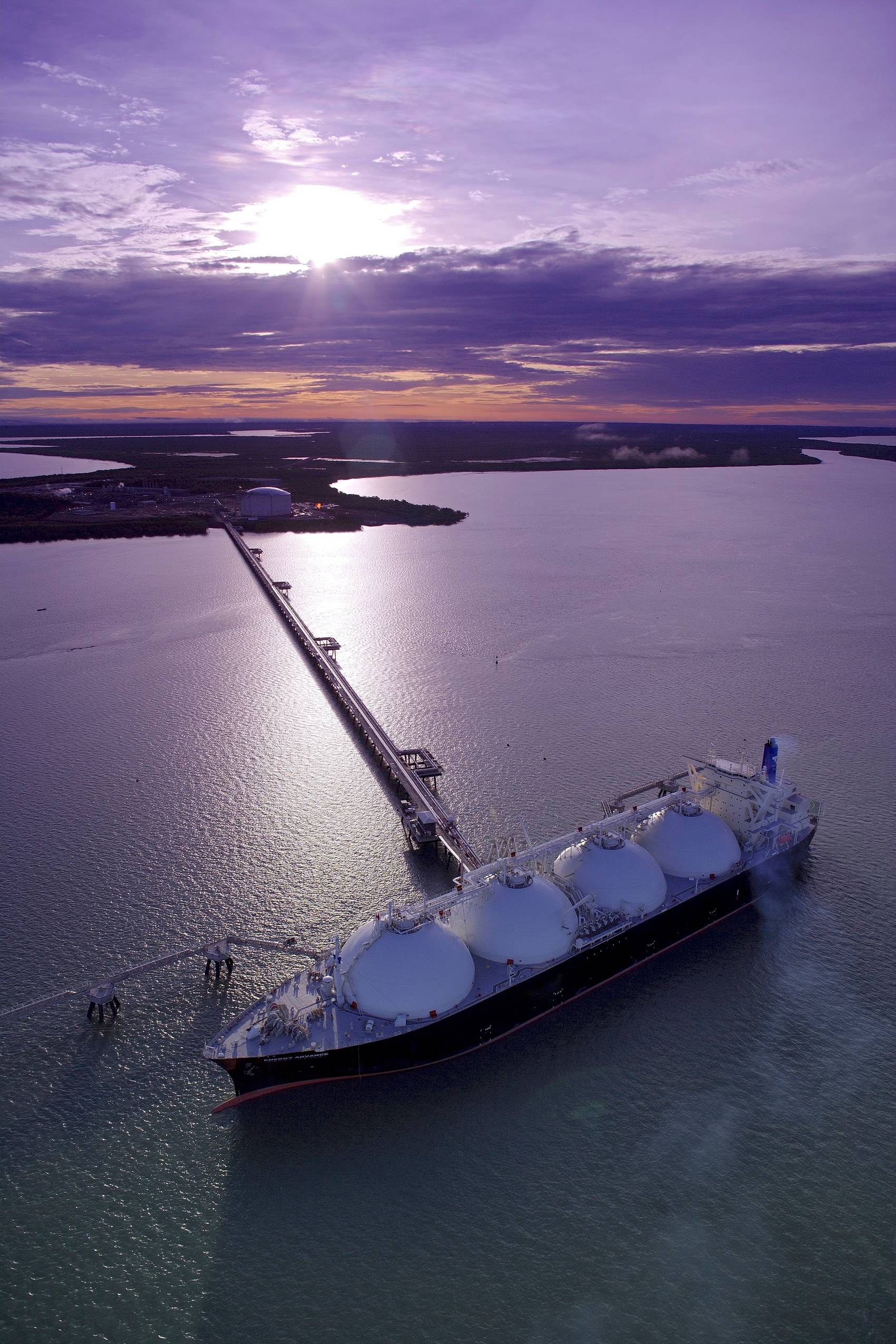 Large ship at sea dock under a purplish sunset sky.