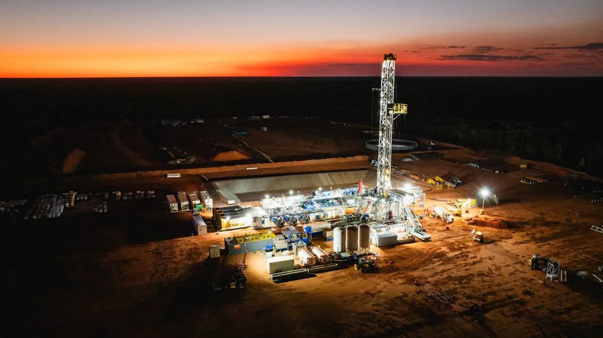 Aerial view of a remote oil drilling site in a vast desert landscape.