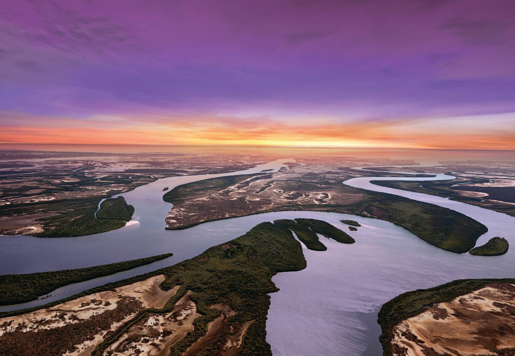 Aerial view of a winding river at sunset with a vibrant sky.