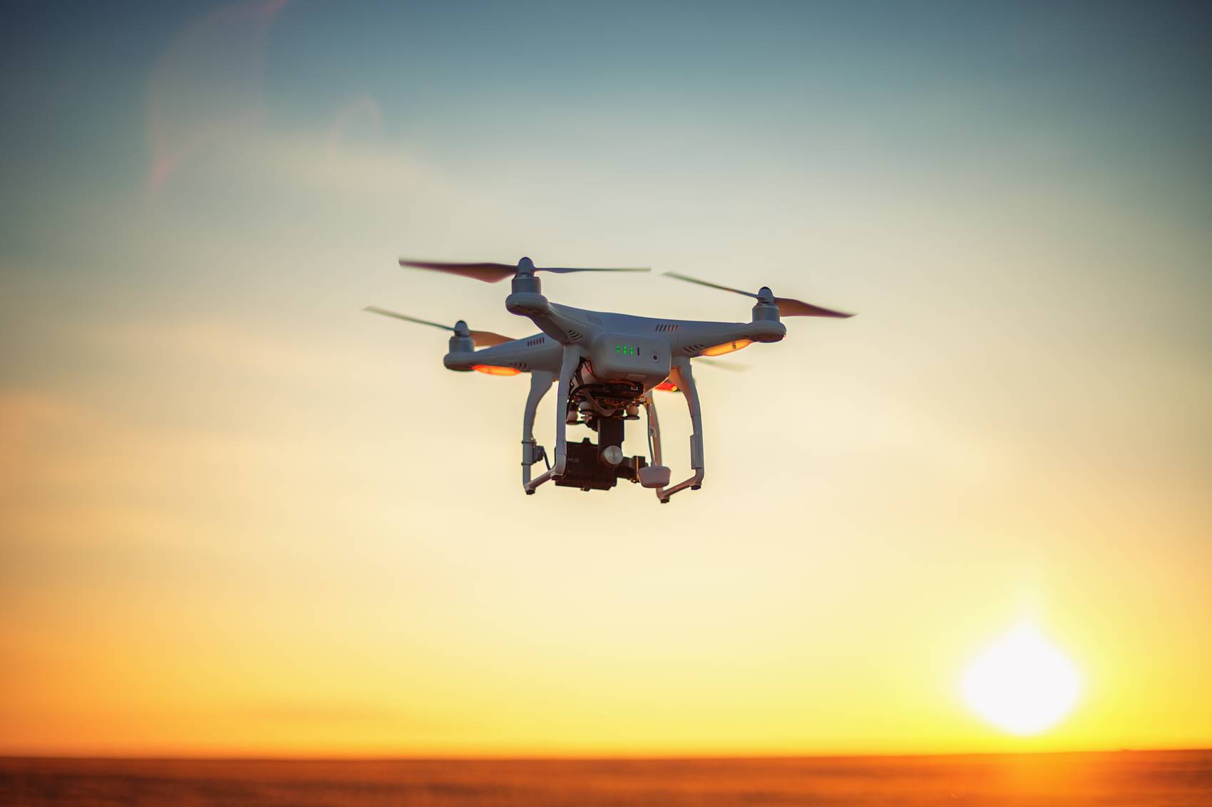 Drone hovering against a warm sunset sky.