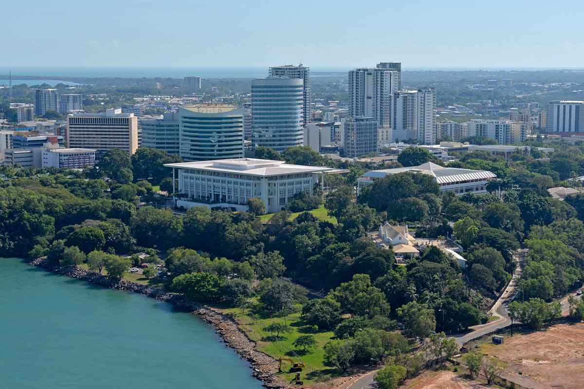 Aerial view of a coastal cityscape with modern buildings and lush greenery.