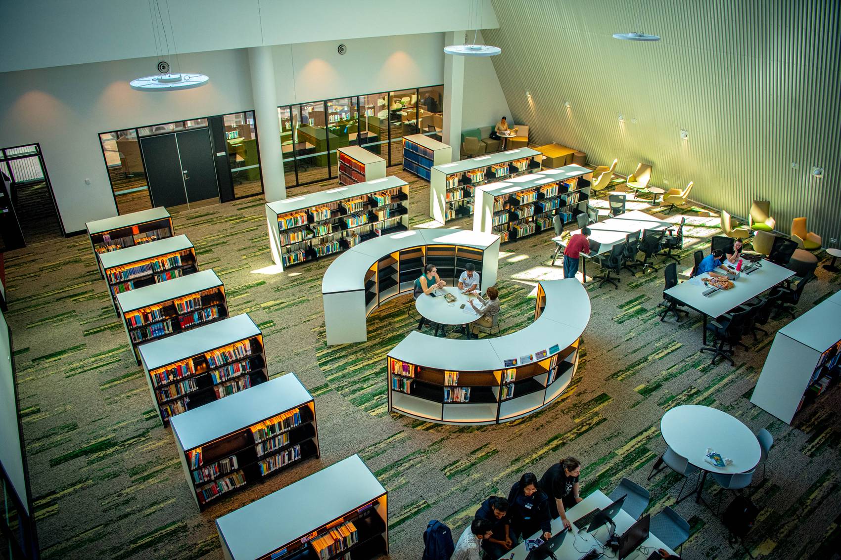 Aerial view of a modern library with circular tables and bookshelves.