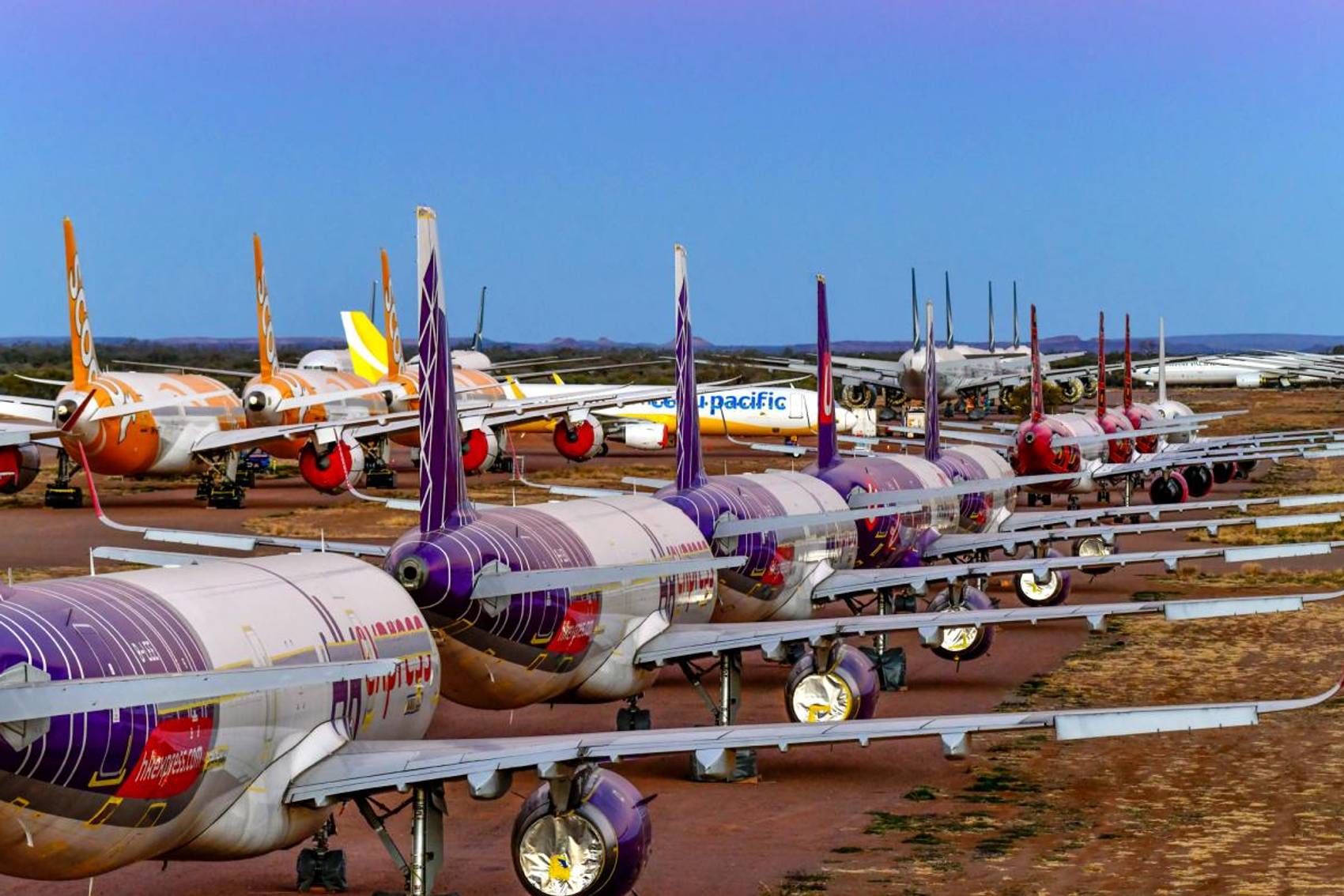 Rows of parked airplanes in a desert, with various airline liveries.