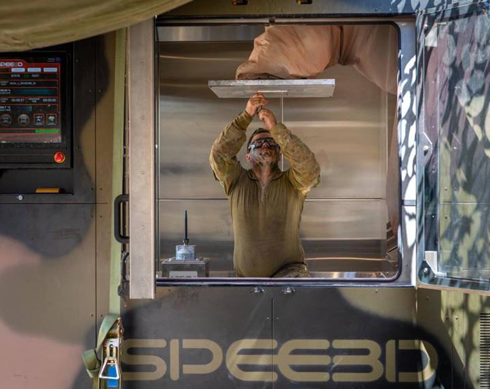 Person working inside a SPEED3D metal 3D printing enclosure.
