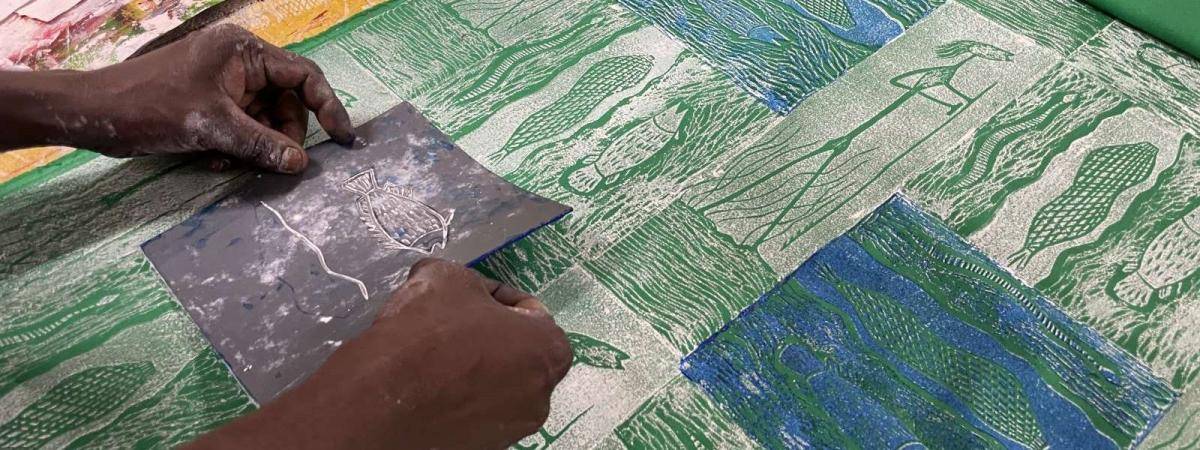 Hands applying a small carved block on a patterned textile.
