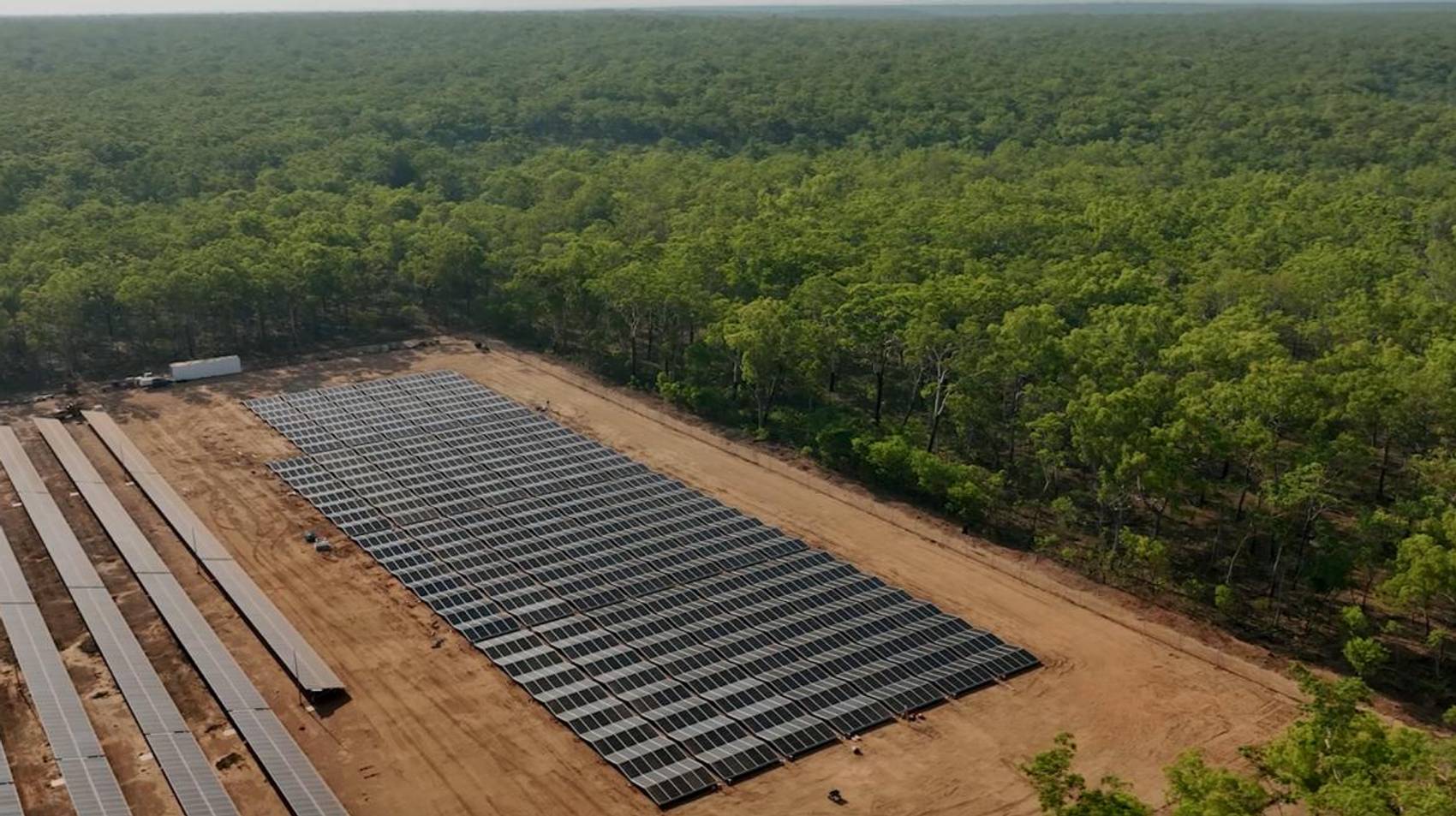 Aerial view of solar panels surrounded by lush green forest.